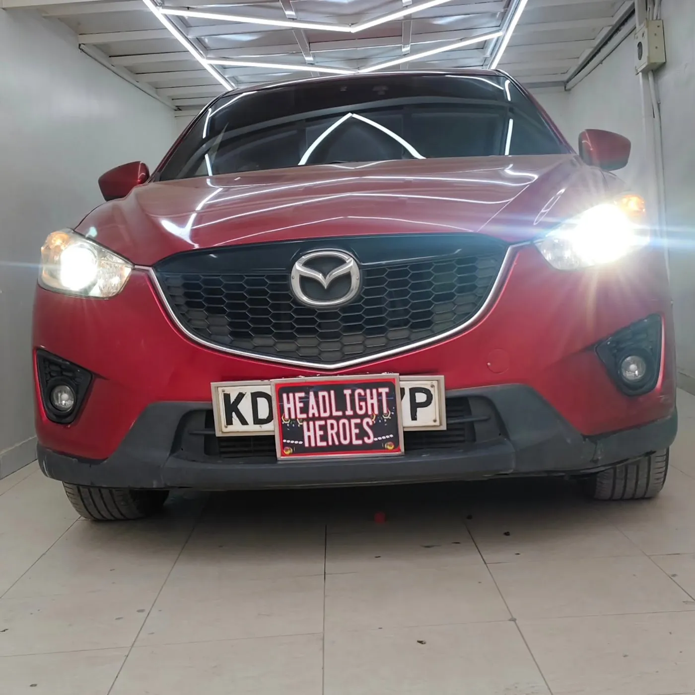 Red Mazda CX-5 in the Headlight Heroes bay with upgraded projector headlights switched on