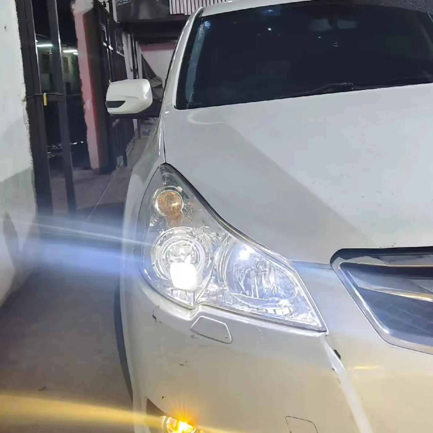 Clear headlight on a white Subaru with the lamp on