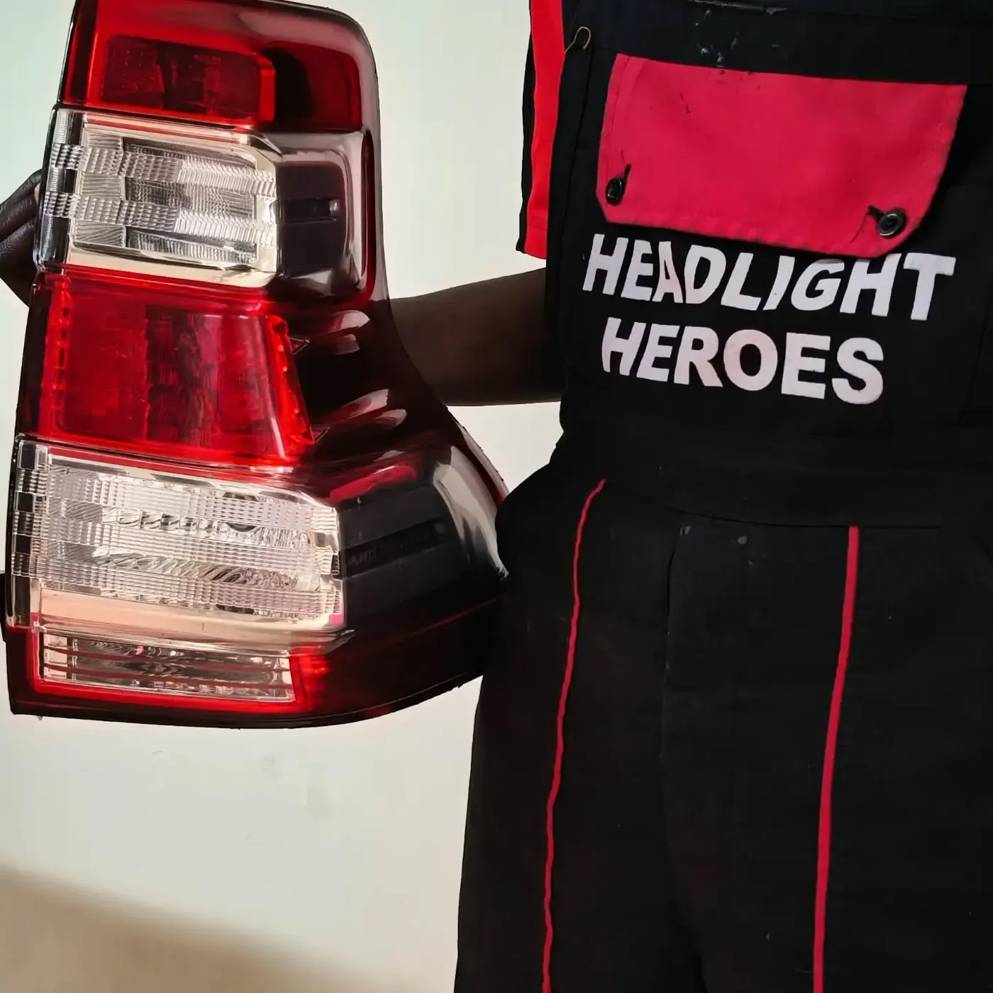 Technician in Headlight Heroes uniform holding a tail light unit